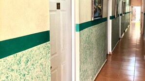 A long hallway with doors on one side and a green stripe on the walls. - Hotel Verano Azul (Santo Domingo)
