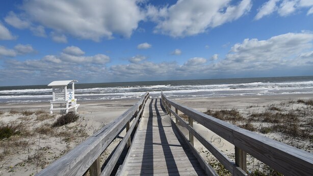 A wooden boardwalk leading to a lifeguard station on a beach with waves in the background. - Enjoy Belle of the Beach -  Your Family Get Away!  **Linens Included** (Carolina Beach)