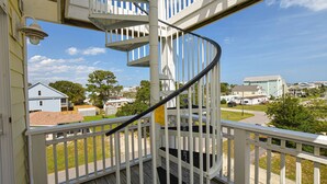 A spiral staircase with white railings and a wooden deck, leading to a balcony with a clear view of a residential area. - Enjoy Belle of the Beach -  Your Family Get Away!  **Linens Included** (Carolina Beach)