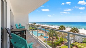 A balcony with turquoise chairs, a pool, and a beach view. - Sterling Sands 313 - On the Beach! Renovated 2B/2B w/Pool/Hot Tub/Garage Parking (Destin)
