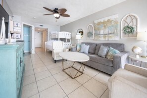 A living room with a white sofa, a grey sofa, a round table, a ceiling fan, and a decorative mirror. - RELAX on the BEACH! 1 Bedroom at Phoenix East on the 9th Floor (Orange Beach)