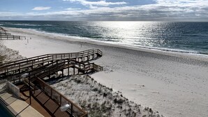 A beach with a wooden boardwalk leading to the shore, sandy beach, and ocean.