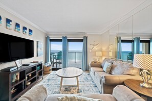 Un salon équipé d’un téléviseur, d’un canapé, d’une table basse et offrant une vue sur la mer.