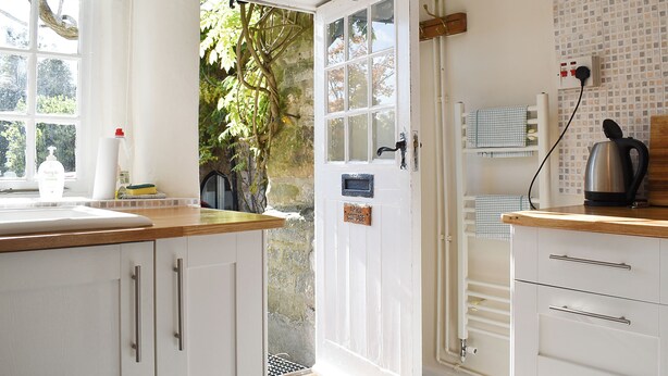 A kitchen with white cabinets, a wooden countertop, a view of greenery outside, a kettle, and a wall-mounted power outlet. - 2 bedroom accommodation in Yougrave, near Bakewell (Yougrave, near Bakewell)