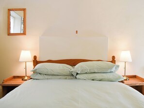 Un lit avec deux lampes de chevet, une tête de lit en bois et un miroir au mur.