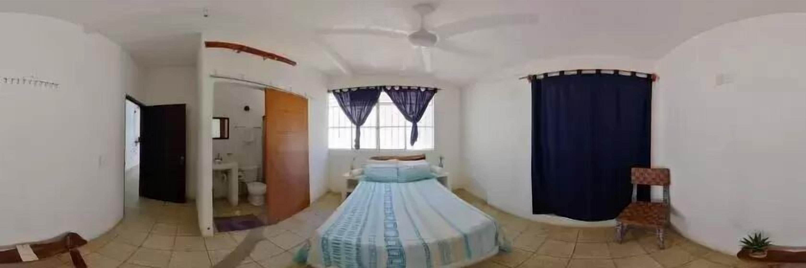 A room with a bed, a chair, a small table, and a window with curtains.