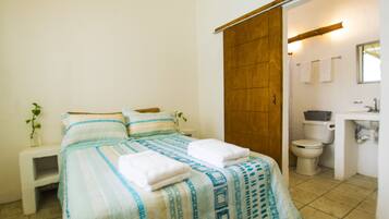 A bedroom with a bed, bedside table, and a bathroom with a toilet and sink.