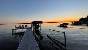 Un muelle se adentra en aguas tranquilas con un atardecer al fondo.