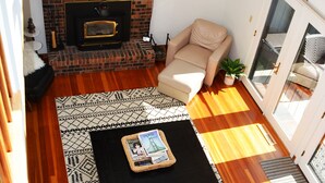 Una sala de estar moderna con una chimenea de ladrillo, un sofá, una mesa de centro y un televisor montado en la pared.