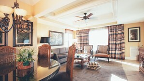 Ein geräumiges Wohnzimmer mit Esstisch, Stühlen, einer Couch und einem Deckenventilator.