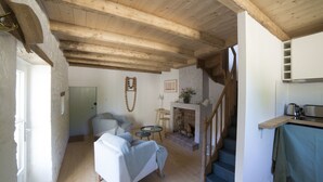 Una sala de estar acogedora con chimenea, una escalera y una zona de cocina.