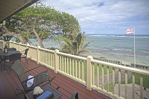 A wooden deck with outdoor furniture, a flag, and a view of the ocean. - True Hawaiian Aloha with modern conveniences (Hauula)