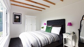 A bedroom with a bed, a nightstand, a lamp, a framed picture, and a door. - Maple Cottage - Gorgeous character filled cottage (KANGAROO VALLEY)
