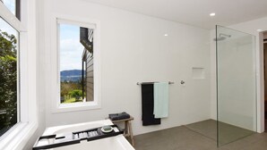 A modern bathroom with a glass shower, a window with a view of the outdoors, and a small table with a towel and a tray. - Maple Cottage - Gorgeous character filled cottage (KANGAROO VALLEY)