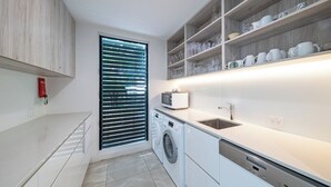 Una cocina moderna con electrodomésticos integrados, lavadora y una repisa con cristalería.