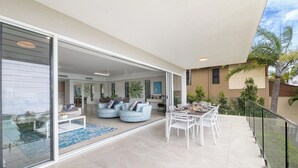 Un espace de vie moderne doté d’une porte coulissante en verre, d’une piscine et d’un coin repas avec des meubles d’extérieur.