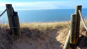 Une plage de sable bordée d’une clôture en bois, offrant une vue dégagée sur l’océan.