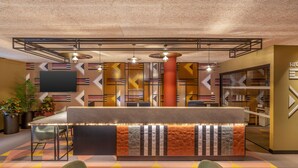 A reception area with a modern design, featuring a reception desk, seating area, and a large flat-screen TV.