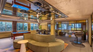 A modern indoor space with a pool table, a sectional sofa, and a billiards table.