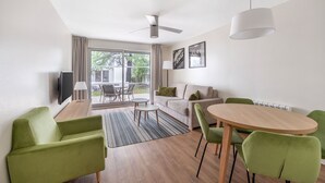 A modern living room with a sofa, chairs, a dining table, and a TV.