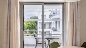 A modern apartment with a sliding glass door leading to a balcony with a dining table and chairs.
