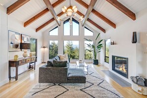 A spacious living room with a high ceiling, large windows, a fireplace, and a modern sofa. - Sonoma Hilltop Estate with Spa (Sonoma)