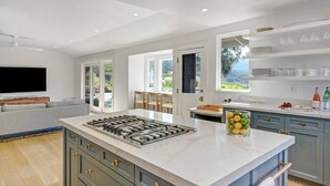 A modern kitchen with a central island, built-in cabinets, and a large window offering a view of the outdoors.