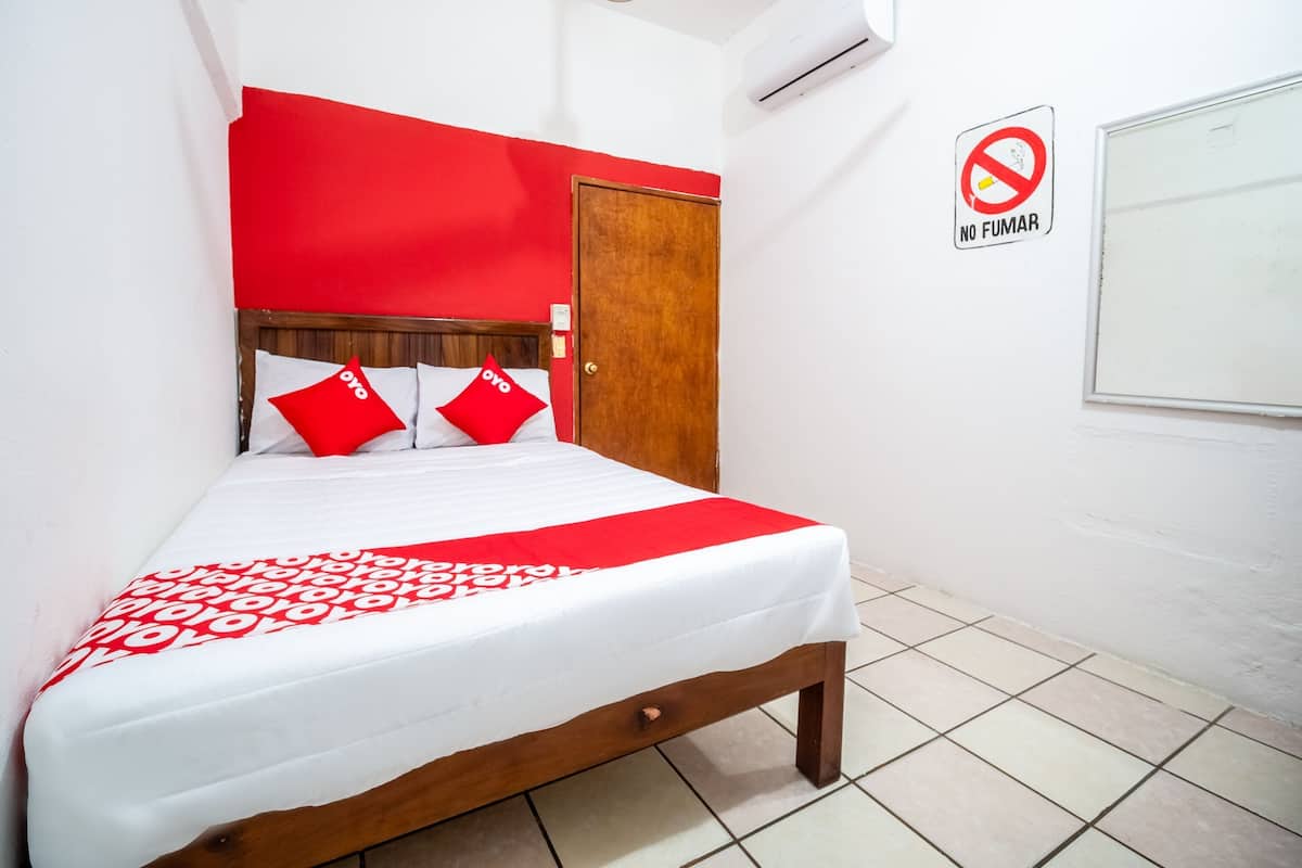 Ein Bett mit rotem Kopfteil, weißer Bettwäsche und einer roten Decke.