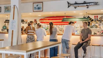 Zona de bar con mostrador, taburetes y un grupo de personas.