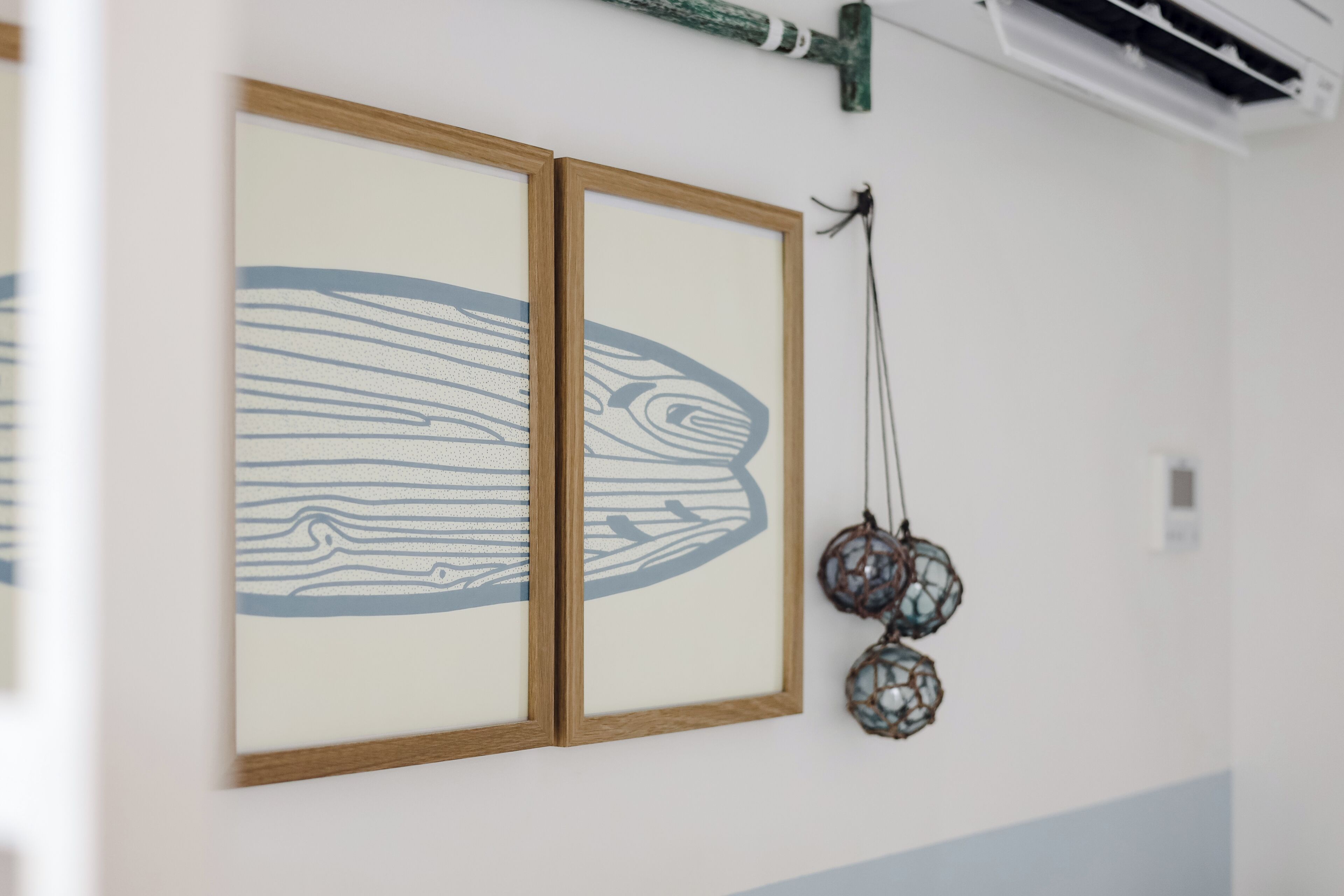 A wall with two framed artworks and a dreamcatcher.
