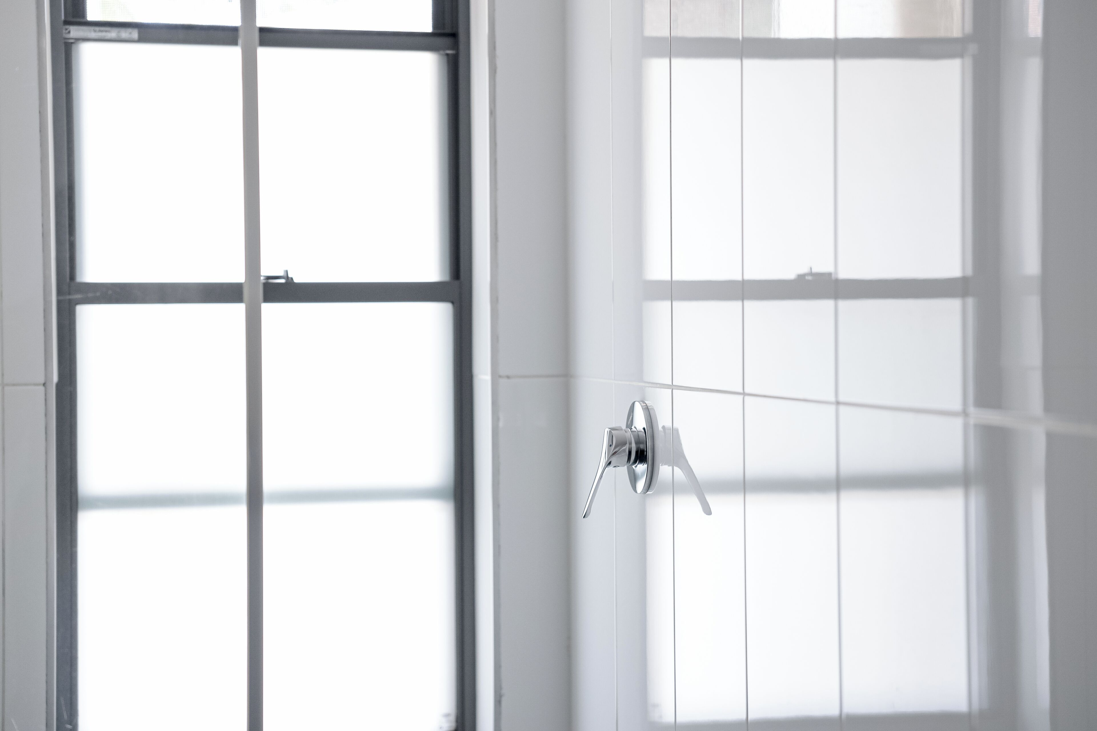 A bathroom with a large window, a shower, and a toilet.