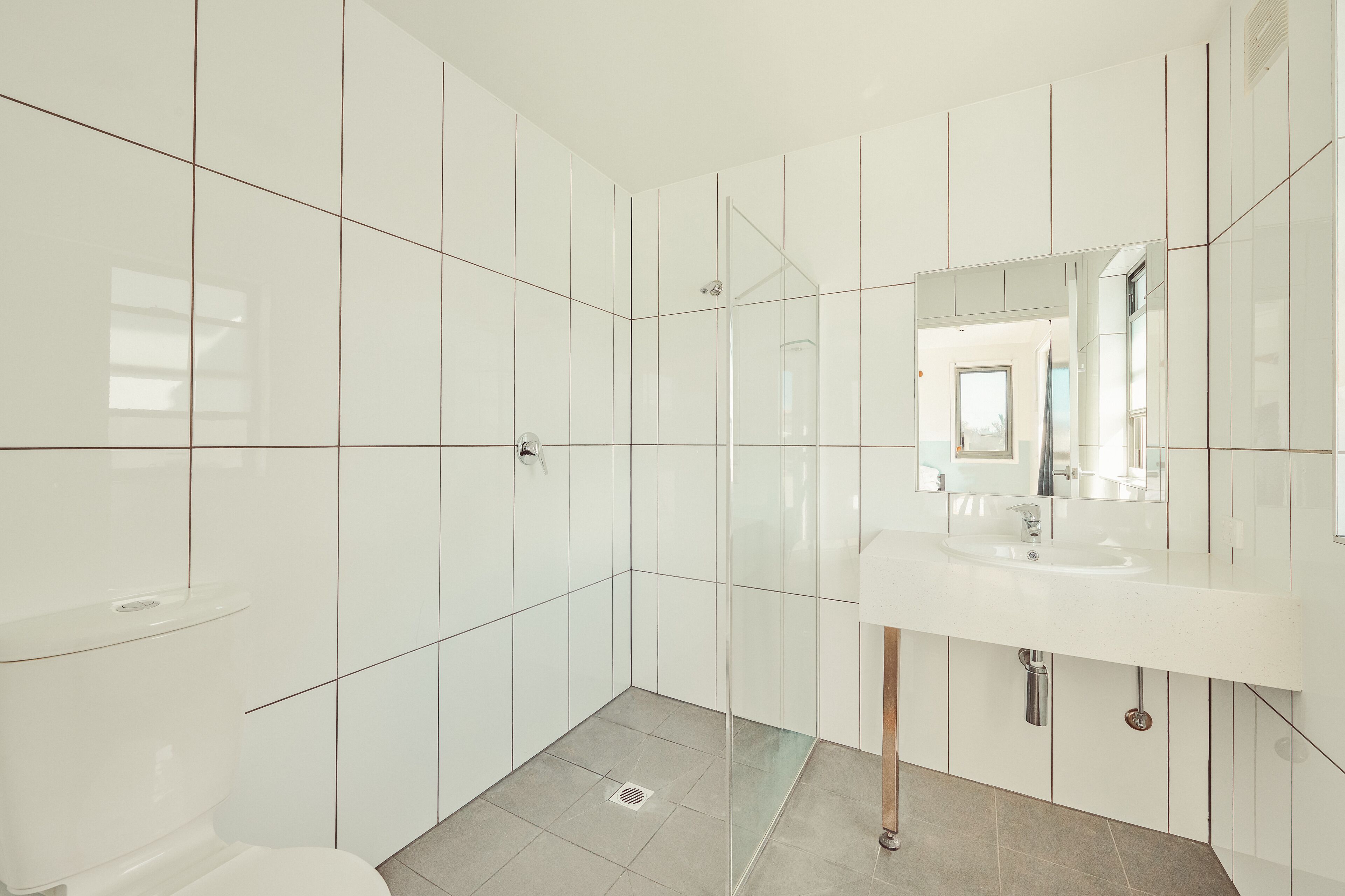 Un baño moderno con inodoro, ducha con puerta de cristal y lavamanos con espejo.
