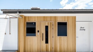 A wooden door with a window, a doorbell, and a sign that reads "Guest Laundry". - The Surf House - Hostel (Byron Bay)