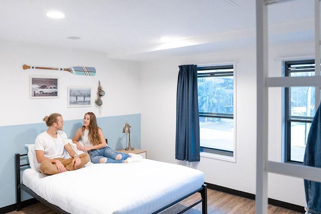 A bedroom with a bed, a nightstand, a lamp, and a window with curtains.