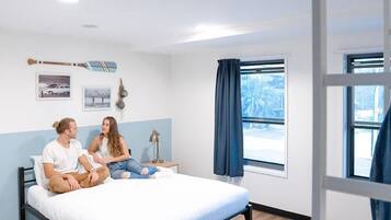 A bedroom with a bed, a nightstand, a lamp, and a window with curtains.
