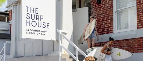 En bygning med et skilt, der viser 'The Surf House', og som indikerer en surfbutik og tagbar.