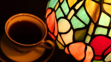 A cup of tea next to a stained glass lamp.