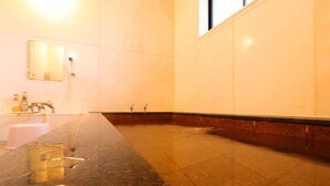 A modern bathroom with a long, dark marble countertop, a sink, and a mirror. - Warabisou (Yuzawa)