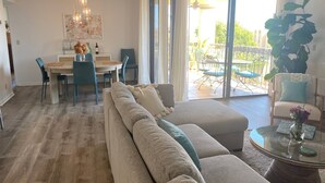 Ein großzügiger Wohnbereich mit einer großen Couch, einem Esstisch mit Stühlen und Blick auf die Terrasse.