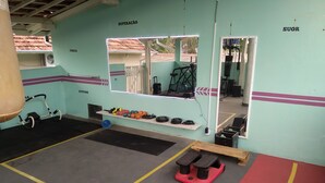 A gym with exercise equipment, a mirror, and a red mat area. - 2 bedroom house near UNESP (Botucatu)