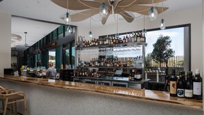 A bar area with a tiled counter, hanging lights, and a variety of bottles and glasses.