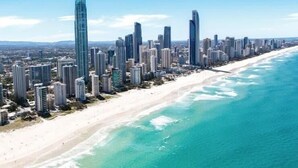 A coastal cityscape with high-rise buildings along a sandy beach.