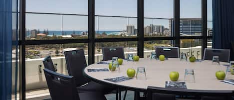 A conference room with a large table, chairs, and a view of the cityscape through large windows.