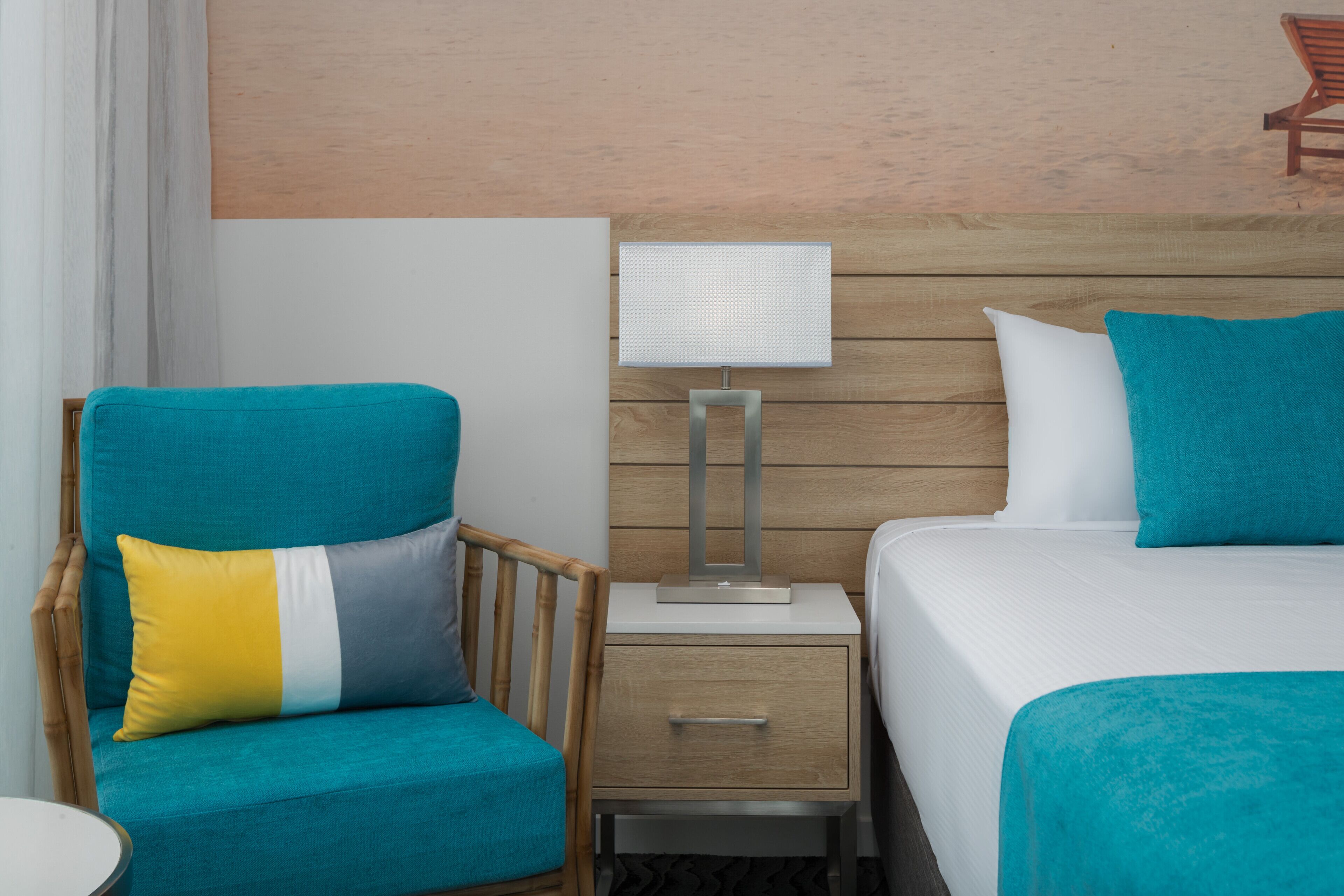A hotel room with a bed, a chair, a nightstand, and a lamp.