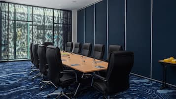 Una sala de conferencias con una larga mesa, sillas negras y una alfombra azul estampada.