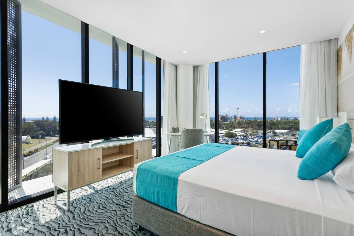 Ein modernes Hotelzimmer mit einem großen Bett, einem Flachbildfernseher und Blick auf die Stadt.