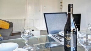 Una mesa de comedor con una botella de vino Hardys Crest Shiraz 2018, una copa y un plato.