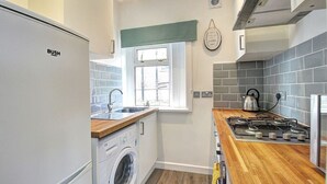 Una cocina funcional con lavadora, pileta, cocina y ventana con vista.