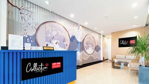 A reception area with a blue counter, decorative wall art, and a sign for Collection Signature by OYO. - Collection O Joy Inn - Near T3 Terminal (Ho Chi Minh City)