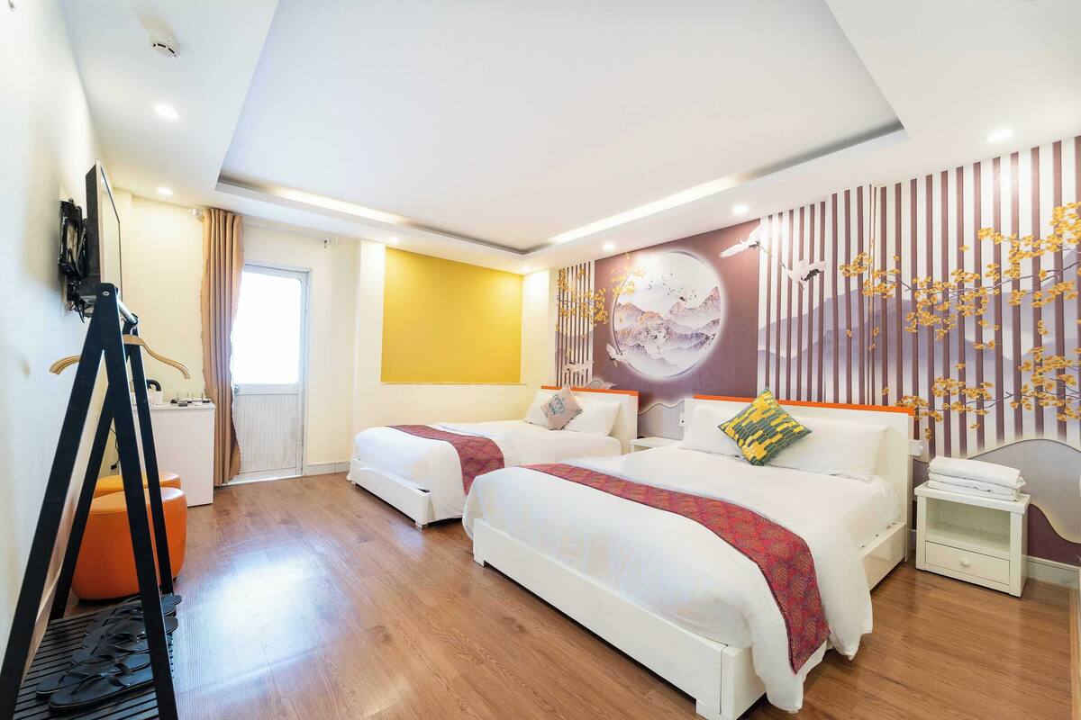A hotel room with two beds, a large window, a wall mural, and a wooden floor.
